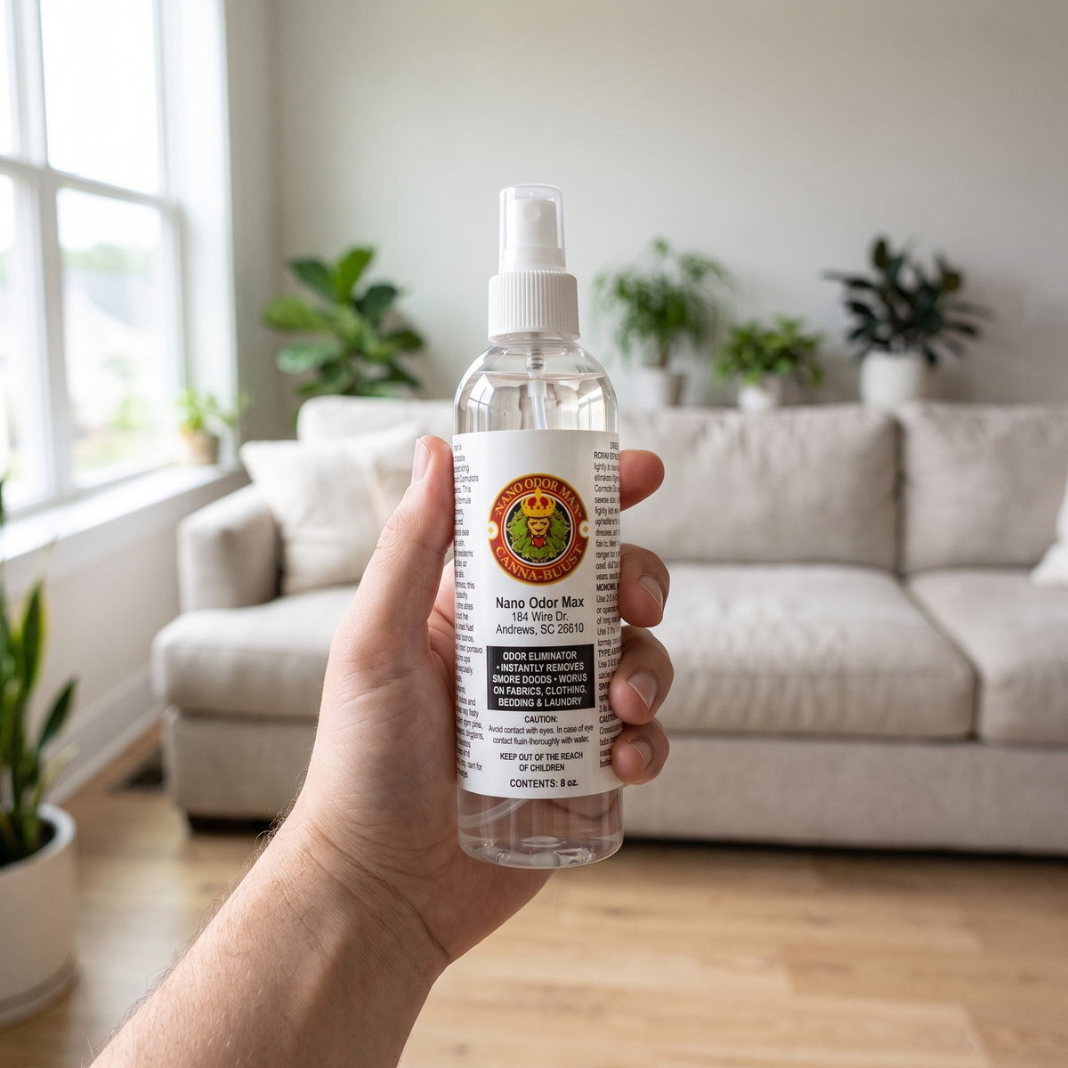 Hand holding a Nano Odor Max spray bottle in a living room
